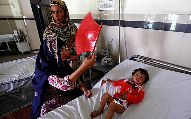mother use hand fan to comfort son in hospital during load shedding